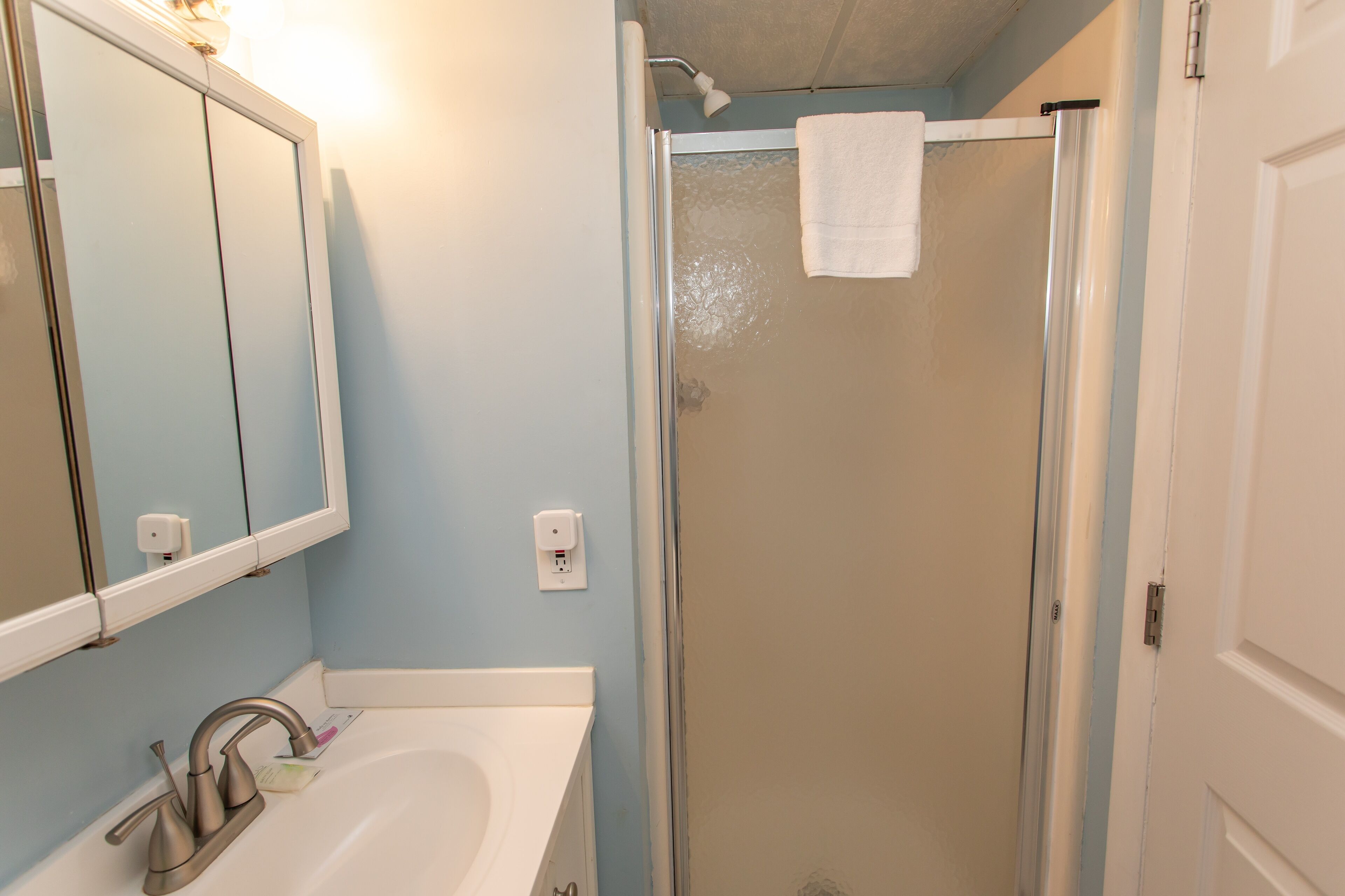 Un baño con lavabo, espejo y ducha.