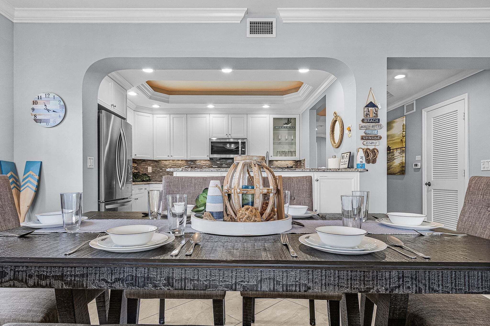 Una cocina moderna con armarios blancos, electrodomésticos de acero inoxidable y una isla central con un elemento decorativo.