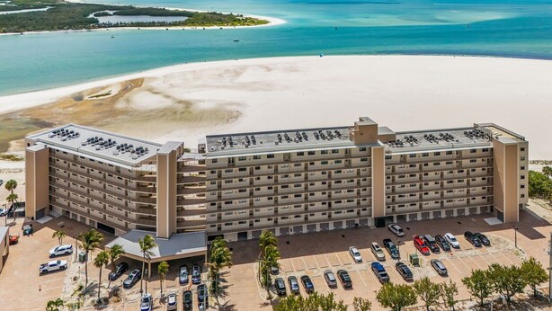 A multi-story hotel with a parking lot and a beach view. - Welcome To Carlos Point # 324 2 Bedroom Condo by RedAwning (Fort Myers Beach)