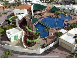 Un resort con una piscina grande, toboganes acuáticos y palmeras.
