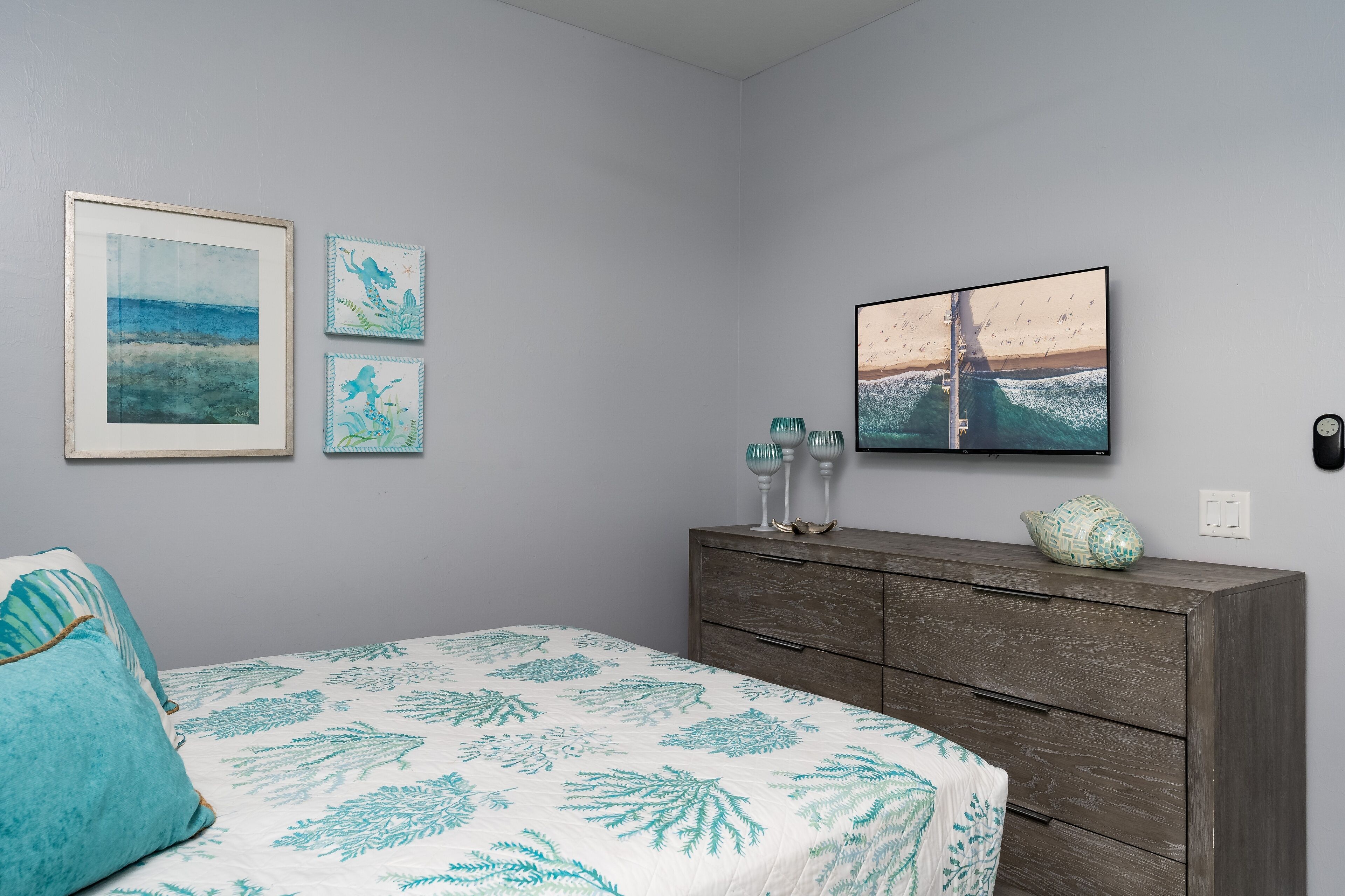 A bedroom with a bed, a dresser, and wall art.