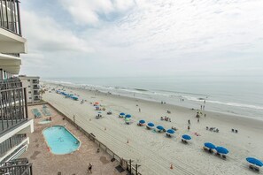 A beach view from a balcony with a pool and beach umbrellas. - Royal Garden Resort 515 2 Bedroom Condo by RedAwning (Murrells Inlet)