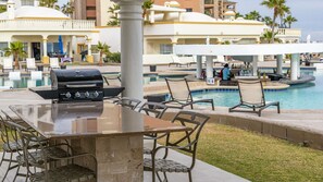 A poolside area with a grill, lounge chairs, and a bar.