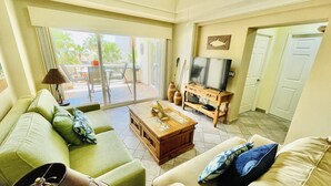 A living room with a sofa, coffee table, TV, and a view of the outdoors. - Beautiful 1 Bedroom Condo on the Sea of Cortez at Las Palmas Resort BN-203B Studio Condo by RedAwning (Puerto Peñasco)