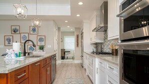 Una cocina moderna con armarios blancos, electrodomésticos de acero inoxidable y una isla central.