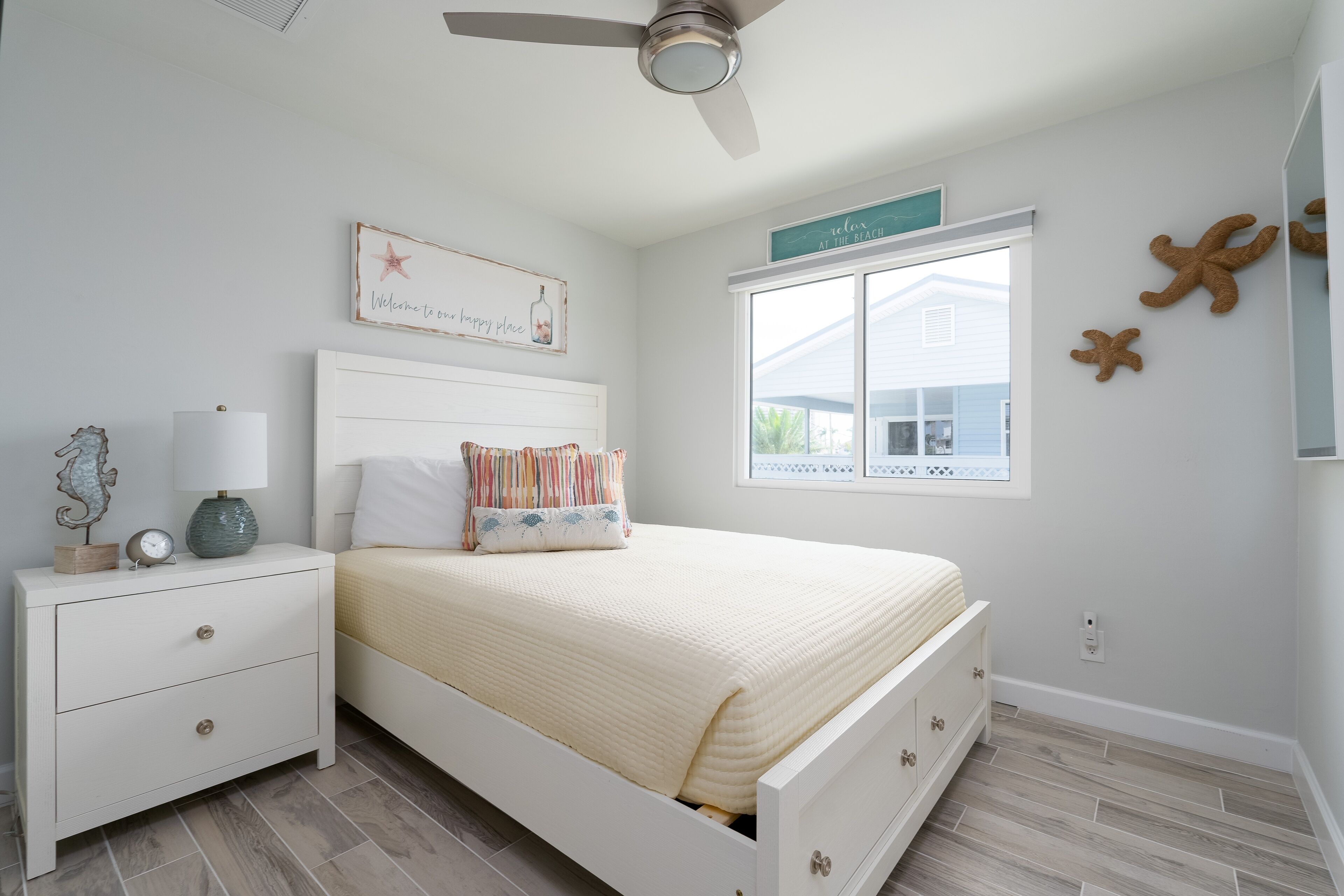 A bedroom with a bed, nightstand, lamp, and decorative items.