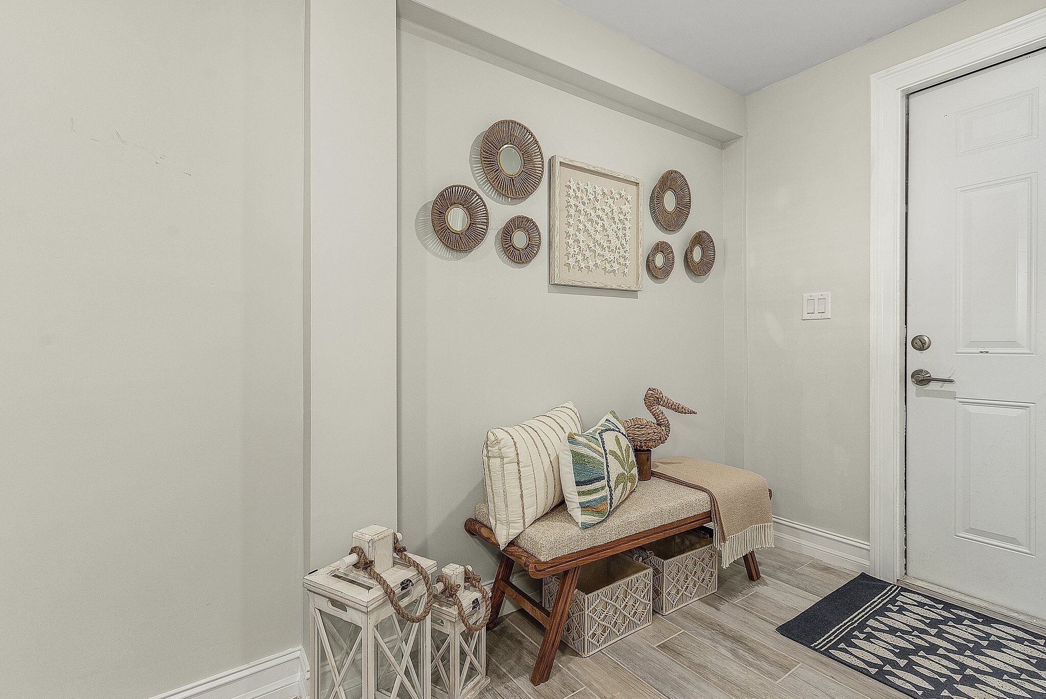 A hallway with a bench, decorative wall art, and a door.