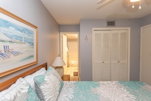 Relax in this serene bedroom with a comfortable bed, a beautiful painting, and a ceiling fan.
