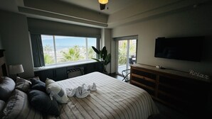 A bedroom with a bed, a desk, a TV, and a view of the beach. - Beautiful 1Â½ Bedroom Condo on the Sea of Cortez at Las Palmas Resort D-304 2 Condo by RedAwning (Puerto Peñasco)