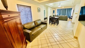 A living room with a leather sofa, a wooden cabinet, and a dining area with a table and chairs. - Spectacular 2 Bedroom Condo on Sandy Beach at Las Palmas Resort D-505 2 Condo by RedAwning (Puerto Peñasco)