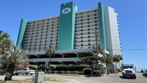Ein mehrstöckiges Hotel mit einem auffälligen Schild mit der Aufschrift "Royal Garden", einer Tiefgarage und Blick auf den Ozean.