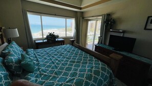 A hotel room with a large bed, a TV, a balcony with a view of the beach, and a window with curtains. - Spectacular 1 Bedroom Condo on Sandy Beach at Las Palmas Resort B-502 1 Condo by RedAwning (Puerto Peñasco)