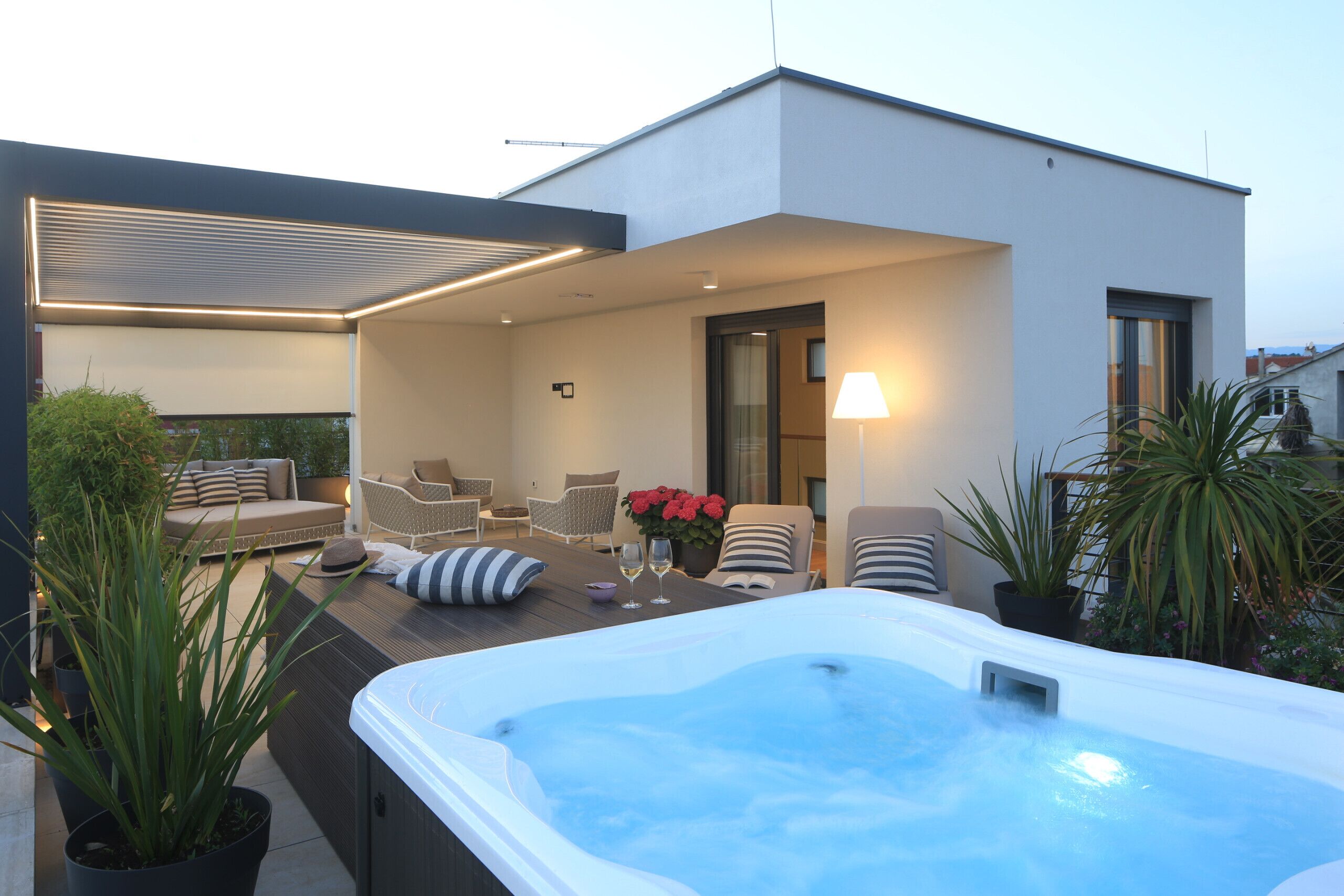 Un espace moderne aménagé à l’extérieur avec un jacuzzi, des sièges et des plantes en pot.