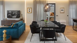 A modern living room with a blue sofa, black chairs, a glass-top dining table, and a large flat-screen TV. - Villa Tereza (Zadar)
