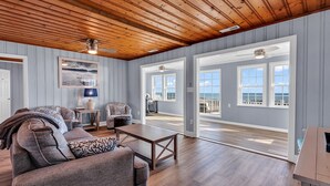A spacious living room with a wooden ceiling, a sofa set, a coffee table, and a view of the ocean through large windows. - Your Personal Oceanfront Resort w/ Heated Pool SP (North Myrtle Beach)