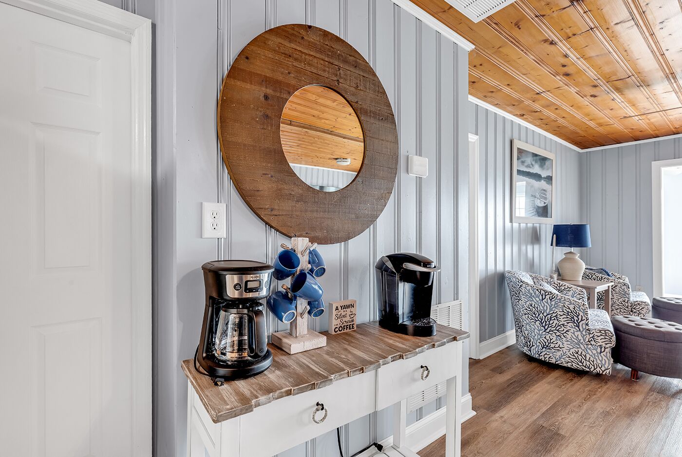 Una sala moderna con una mesa de centro de madera, una cafetera y un soporte azul para tazas.