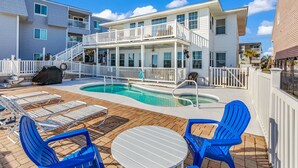 A pool area with lounge chairs and a table, surrounded by a white fence. - Your Personal Oceanfront Resort w/ Heated Pool SP (North Myrtle Beach)