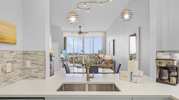 A modern kitchen with a large island, stainless steel appliances, and pendant lighting. - Palm Harbor Penthouse With Marina Views 2 Bedroom Condo by RedAwning (Fort Myers Beach)