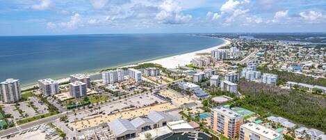 A coastal cityscape with a marina, high-rise buildings, and a beach.