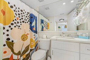 A bathroom with a toilet, sink, and mirror. - Beautiful Penthouse Condo - Corner Unit! 2 Bedroom Condo by RedAwning (Fort Myers Beach)