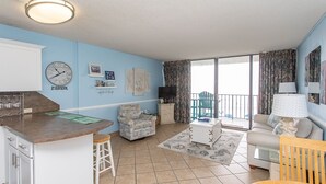 A living room with a kitchen area, a dining table, and a sofa. - Royal Garden Resort 209 2 Bedroom Condo by RedAwning (Murrells Inlet)