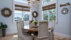 A dining area with wicker chairs, a glass table, and a chandelier. - Beautiful Home With Private Pool On The North End Of Fort Myers Beach! 4 Bedroom Home by RedAwning (Fort Myers Beach)