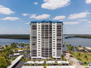 A high-rise hotel with a modern design, featuring multiple balconies and a view of a lake.