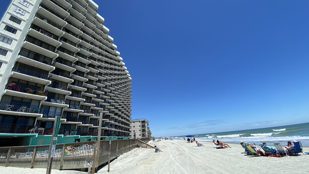 A beachfront hotel with multiple balconies and a sandy beach in the background.