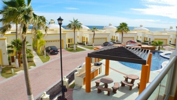A resort with a pool area, outdoor seating, and palm trees. - Spectacular 2 Bedroom Condo on Sandy Beach at Las Palmas Resort G-201 2 Condo by RedAwning (Puerto Peñasco)