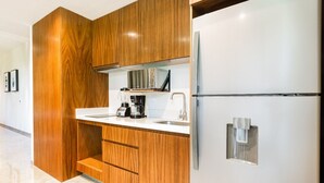 Eine moderne Küche mit Holzschnitzereien, einem Edelstahlkühlschrank, einer eingebauten Mikrowelle und einer Kaffeemaschine.