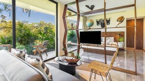 Ein modernes Wohnzimmer mit großem Fernseher, bequemen Sitzmöglichkeiten und Blick auf üppiges Grün.