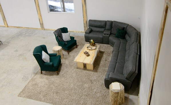A living room with a sectional sofa, two armchairs, a coffee table, and a small wooden side table.