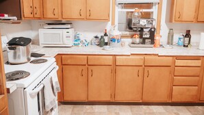 Una cocina con armarios de madera, una estufa blanca, un microondas y varios utensilios de cocina sobre la encimera.
