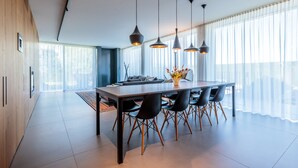 A modern dining area with a long table, black chairs, and pendant lighting. - [LUXURY] VILLA Rubin with POOL, GYM & SPA (Arzergrande)