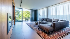 A modern living room with a sofa, a coffee table, and a large window with sheer curtains. - [LUXURY] VILLA Rubin with POOL, GYM & SPA (Arzergrande)