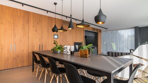 A modern kitchen with a wooden wall, black chairs, a dark table, and pendant lights. - [LUXURY] VILLA Rubin with POOL, GYM & SPA (Arzergrande)