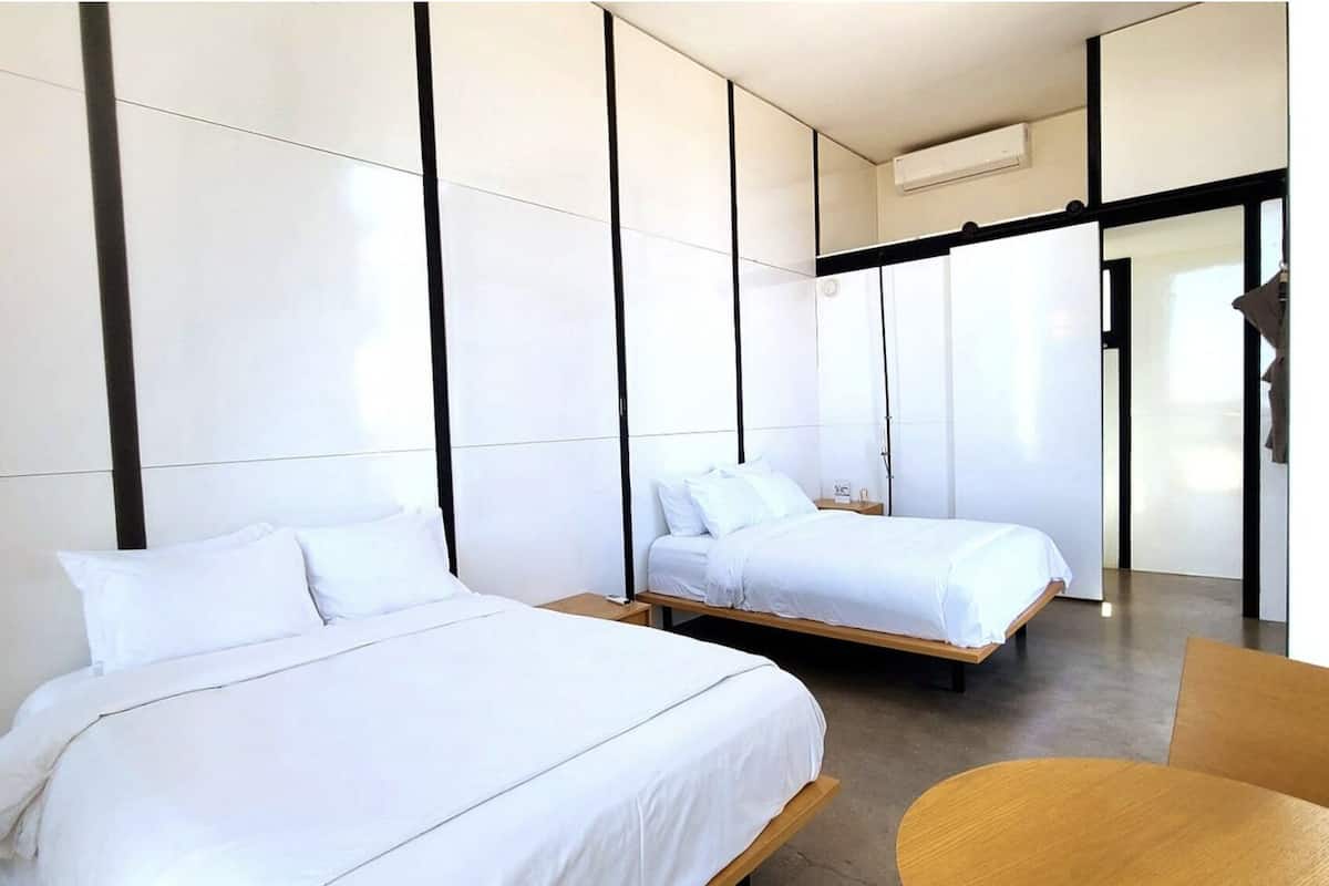 Une chambre d’hôtel moderne avec deux lits, une table en bois et une grande fenêtre.