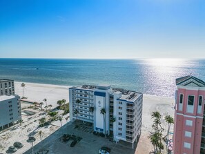 Ein Hotel direkt am Strand mit mehreren Etagen, einem Parkplatz und Blick auf den Ozean.