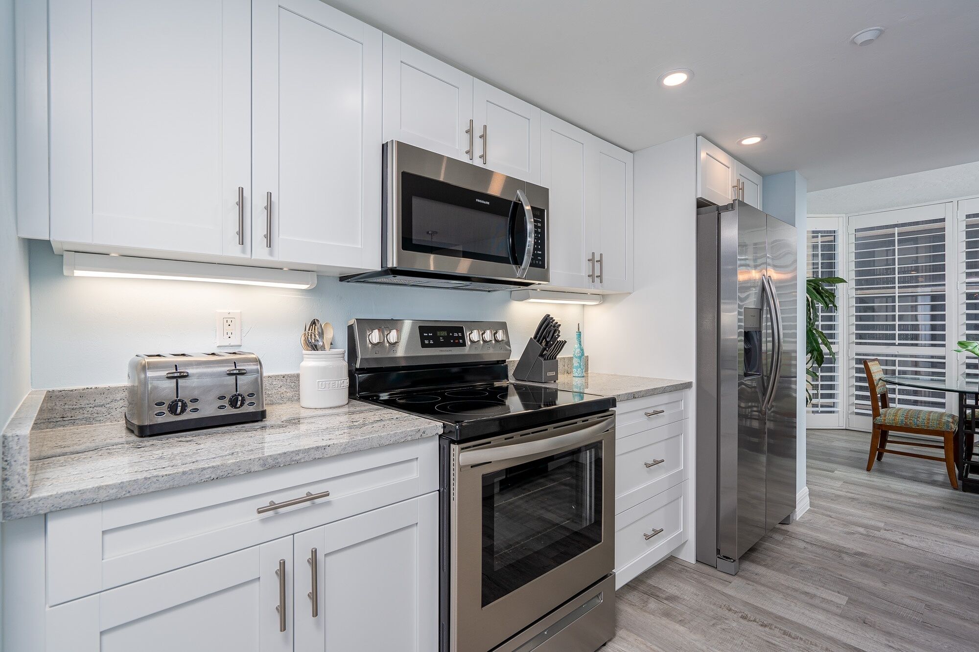 A modern kitchen with white cabinets, stainless steel appliances, and a granite countertop.