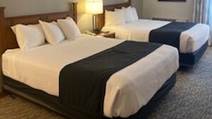 Una habitación de hotel con dos camas, una mesita de noche con una lámpara y un cuadro enmarcado en la pared.