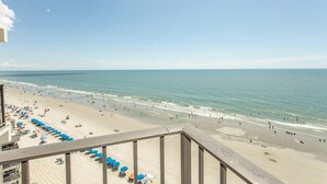 A beach with umbrellas and people, a clear sky, and a view of the ocean. - Royal Garden Resort 1007 1 Bedroom Condo by RedAwning (Murrells Inlet)
