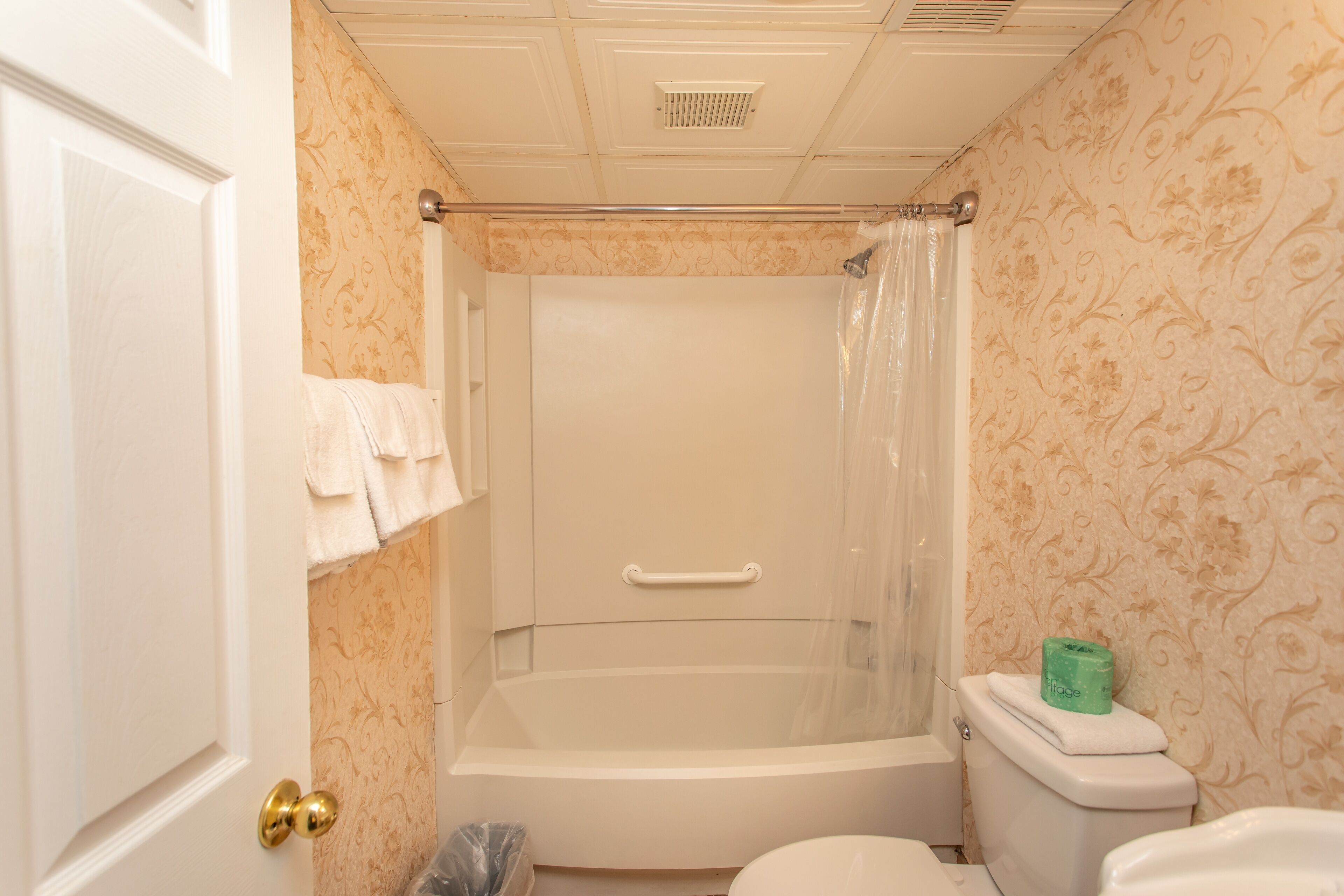 A bathroom with a bathtub, toilet, and shower curtain.