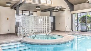 A swimming pool with a hot tub, clear water, and a tiled wall with a sign. - Pelican Pointe|Beachfront|Gulf Views|Indoor Pool (Orange Beach)