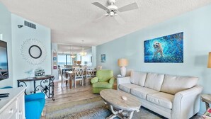 A living room with a sofa, coffee table, and a painting on the wall. - Pelican Pointe|Beachfront|Gulf Views|Indoor Pool (Orange Beach)