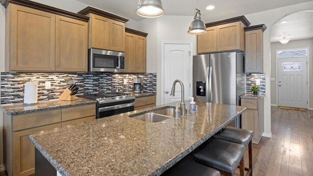 A modern kitchen with granite countertops, stainless steel appliances, and wooden cabinets. - Modern Family Friendly House (Kennewick)