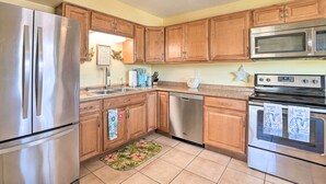 Una cocina con armarios de madera, electrodomésticos de acero inoxidable y suelo de baldosas.