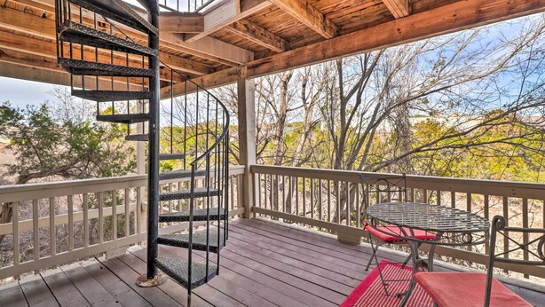 A wooden deck with a spiral staircase, a table with chairs, and a red rug. - Lakefront Home w/ Point Venture Golf Access! (Point Venture)