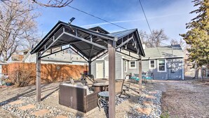 A covered outdoor patio with a grill and seating area, surrounded by a stone and gravel pathway. - Grand Junction Vacation Rental w/ Fire Pit! (Grand Junction)