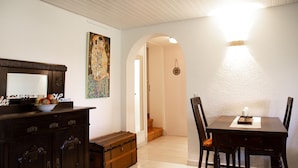 Ein Essbereich mit Tisch und Stühlen, eine Holzkommode mit Schubladen, ein Bild an der Wand und eine Treppe, die in einen anderen Raum führt.