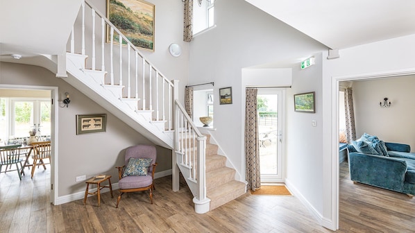 Un grand salon avec un escalier, un coin repas avec une table et des chaises, et un canapé bleu.